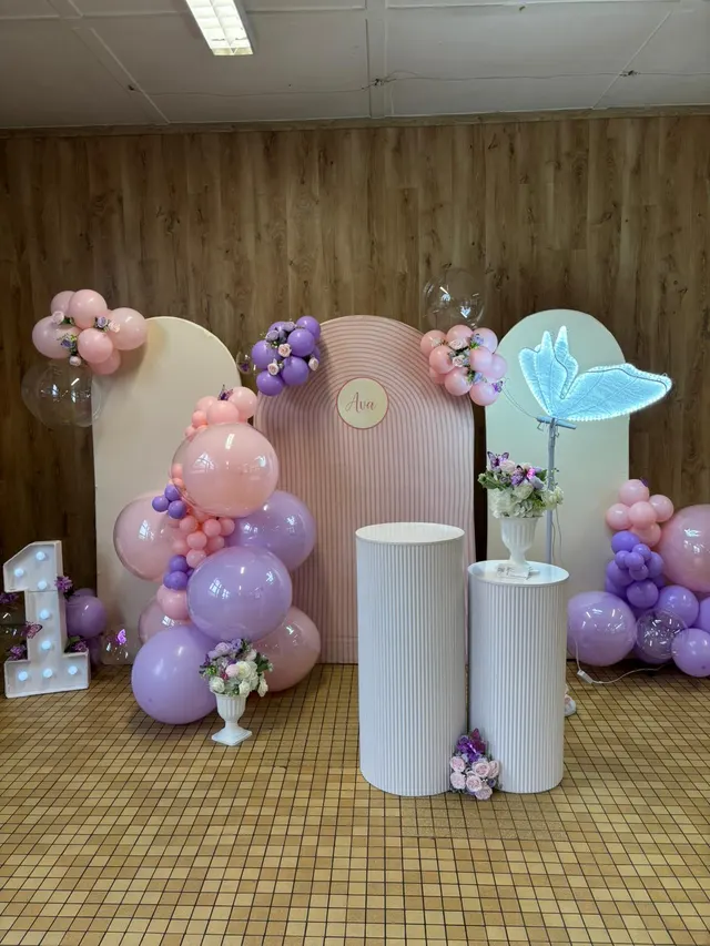 Décoration de premier anniversaire aux tons pastel : arches, ballons roses et violets et chiffre 1 lumineux