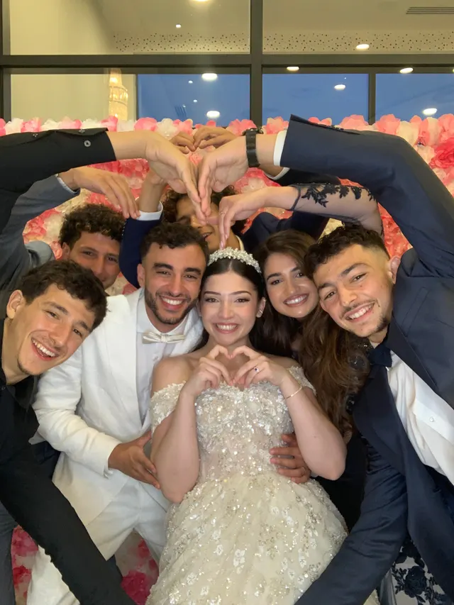 Au photobooth d'un mariage, la mariée et ses amis forment des cœurs avec leurs mains